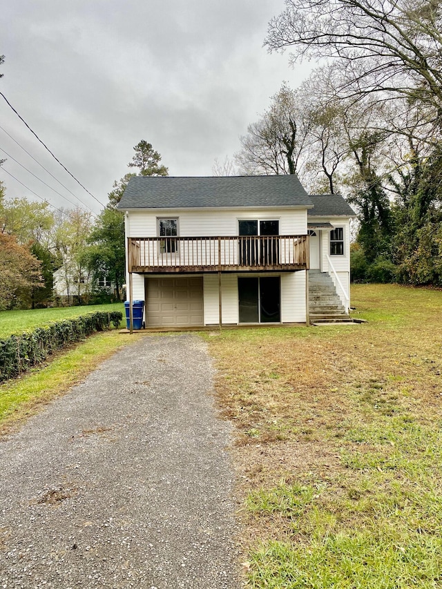 view of front of home featuring a front yard, a garage, and a wooden deck