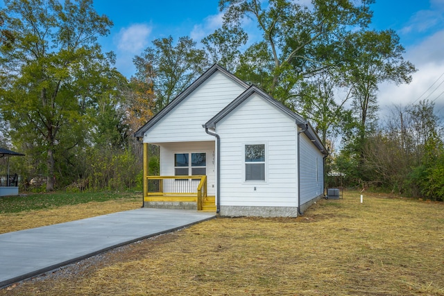 exterior space featuring a porch, a front yard, and cooling unit