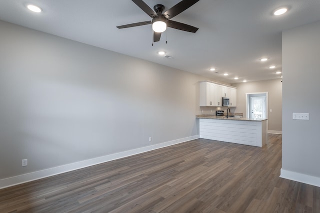 unfurnished living room with ceiling fan, sink, and dark wood-type flooring