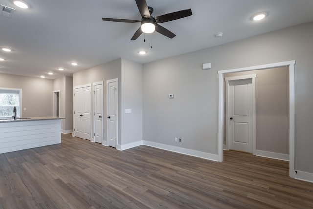 unfurnished living room with dark hardwood / wood-style floors, ceiling fan, and sink