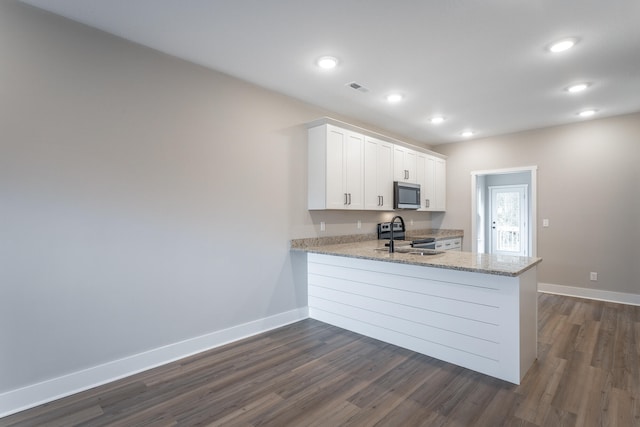 kitchen with kitchen peninsula, white cabinetry, dark hardwood / wood-style flooring, and stainless steel appliances