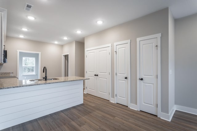 kitchen with dark hardwood / wood-style floors, light stone counters, white cabinetry, and sink