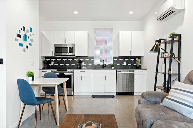 kitchen featuring a wall mounted air conditioner, appliances with stainless steel finishes, decorative backsplash, and white cabinetry