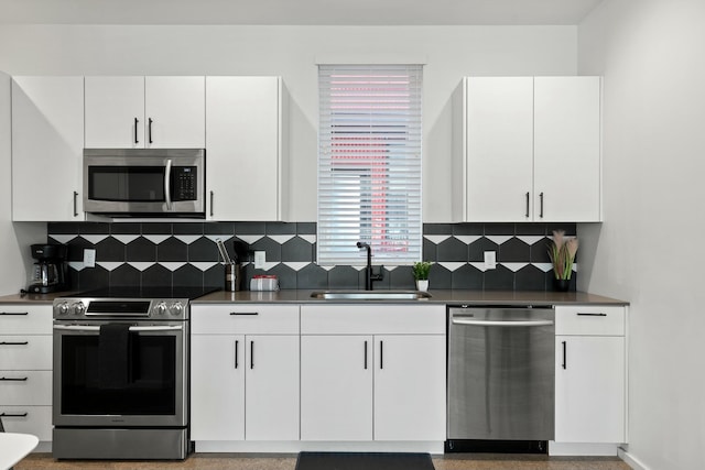 kitchen featuring white cabinets, appliances with stainless steel finishes, backsplash, and sink