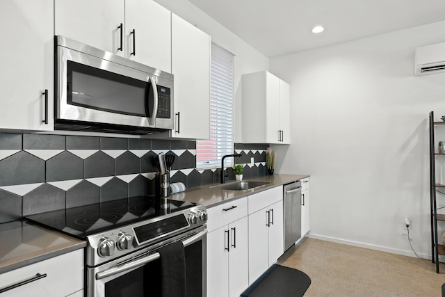 kitchen with appliances with stainless steel finishes, white cabinetry, an AC wall unit, and sink