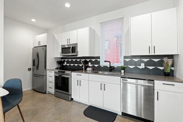 kitchen with tasteful backsplash, sink, white cabinets, and appliances with stainless steel finishes