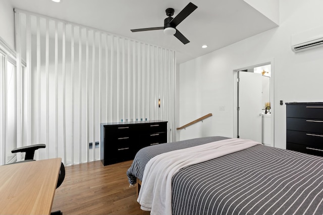 bedroom featuring wood-type flooring, an AC wall unit, and ceiling fan