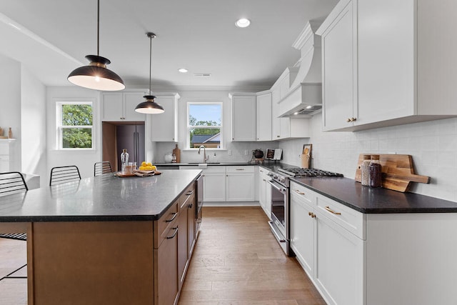 kitchen featuring a wealth of natural light, a center island, white cabinets, and high end stainless steel range oven