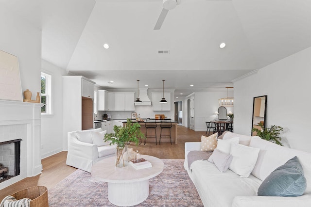 living room featuring ceiling fan, vaulted ceiling, and light wood-type flooring