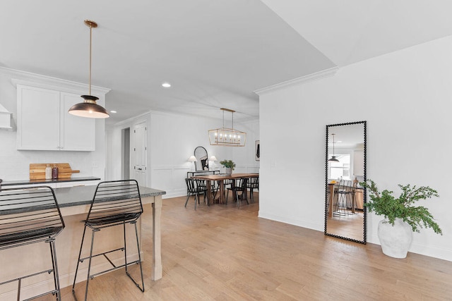 kitchen with white cabinetry, a breakfast bar, light hardwood / wood-style floors, and ornamental molding