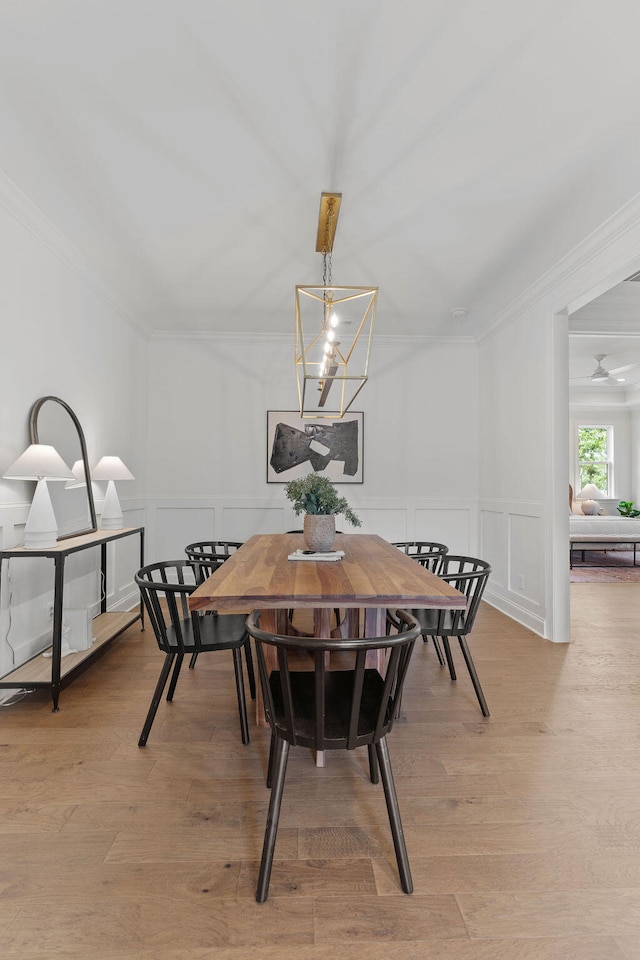 dining area with a chandelier, light wood-type flooring, and ornamental molding