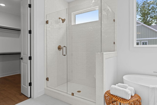 bathroom with a wealth of natural light, shower with separate bathtub, and hardwood / wood-style flooring