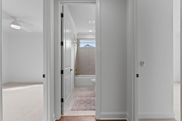 hallway featuring ornamental molding and light tile patterned floors