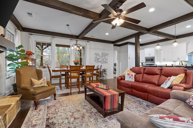 living room with hardwood / wood-style floors, ceiling fan with notable chandelier, washer / dryer, and beamed ceiling