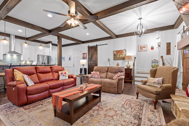 living room featuring light wood-type flooring, a barn door, ceiling fan with notable chandelier, and beamed ceiling