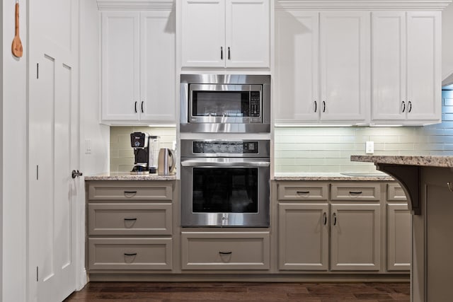 kitchen with white cabinets, dark hardwood / wood-style floors, light stone countertops, and stainless steel appliances