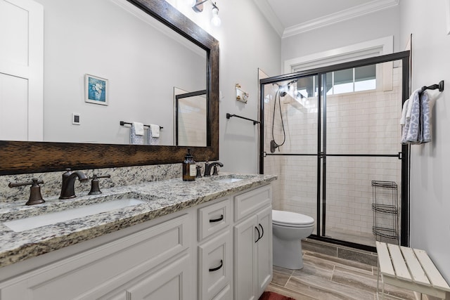 bathroom with crown molding, a shower with door, vanity, and toilet