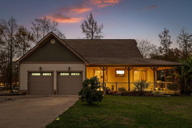 view of front of property featuring covered porch, a garage, and a lawn