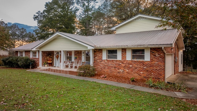 ranch-style house featuring a porch, a garage, and a front yard