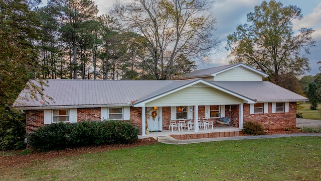 ranch-style house featuring covered porch and a front yard