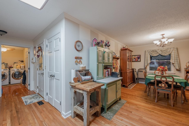 kitchen featuring green cabinets, washing machine and dryer, crown molding, and light hardwood / wood-style flooring