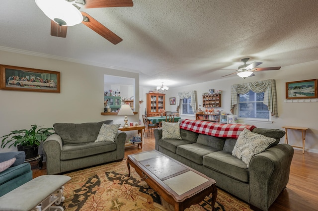 living room with ceiling fan with notable chandelier, wood-type flooring, a textured ceiling, and ornamental molding