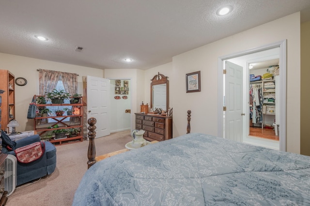 carpeted bedroom with a walk in closet, a closet, and a textured ceiling