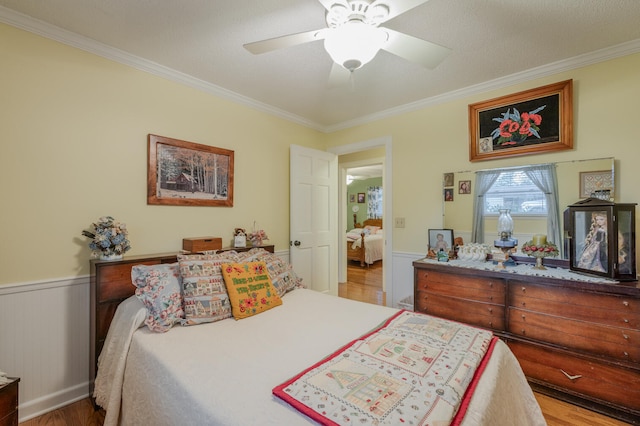 bedroom featuring ceiling fan, crown molding, hardwood / wood-style floors, a textured ceiling, and wooden walls