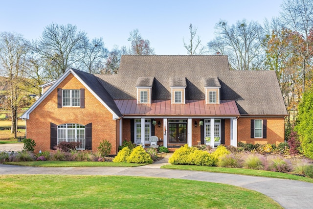 cape cod home featuring a front lawn