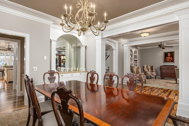 dining area featuring hardwood / wood-style floors, ceiling fan with notable chandelier, crown molding, and decorative columns