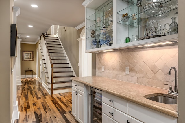 bar with white cabinetry, sink, wine cooler, crown molding, and wood-type flooring