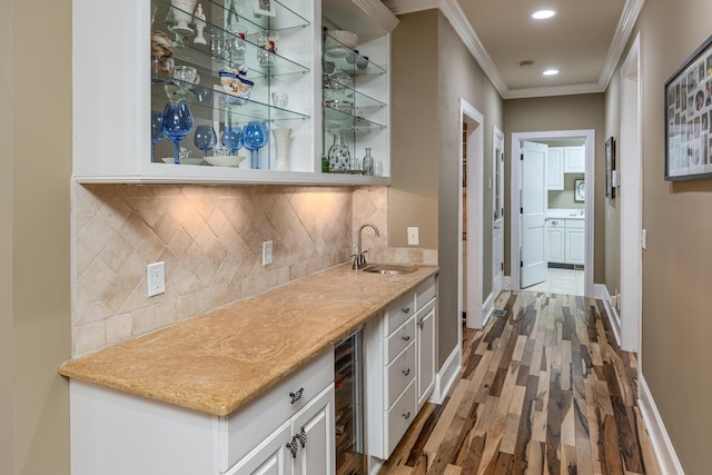 bar with wood-type flooring, crown molding, sink, wine cooler, and white cabinetry