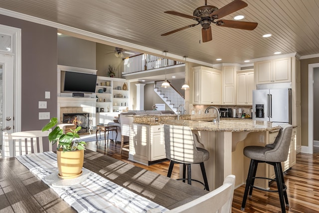 kitchen with a kitchen breakfast bar, hanging light fixtures, light stone counters, kitchen peninsula, and wood ceiling