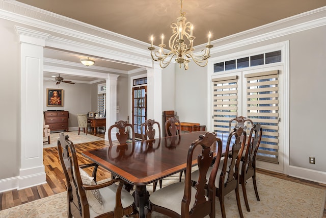 dining space featuring decorative columns, light hardwood / wood-style flooring, ceiling fan with notable chandelier, and ornamental molding