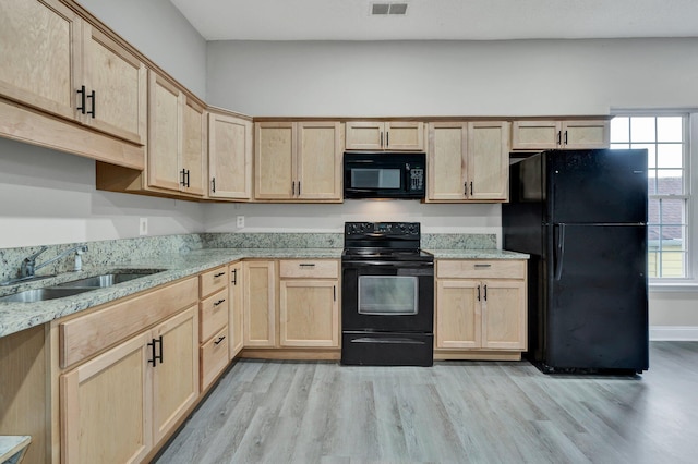 kitchen with black appliances, sink, light brown cabinetry, light hardwood / wood-style floors, and light stone counters