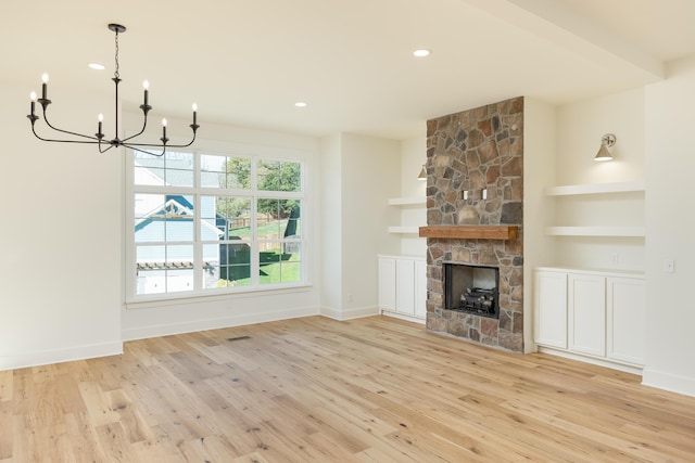 unfurnished living room featuring a fireplace, an inviting chandelier, and light hardwood / wood-style flooring