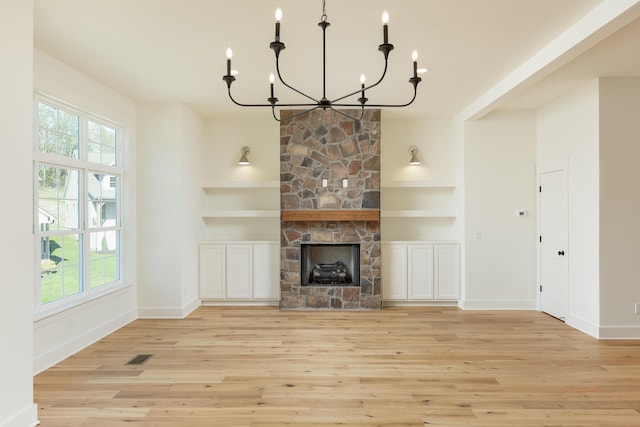 unfurnished living room with a fireplace, a healthy amount of sunlight, a notable chandelier, and light wood-type flooring