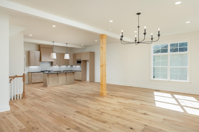 kitchen featuring decorative backsplash, sink, decorative light fixtures, light hardwood / wood-style flooring, and a center island