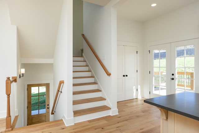 stairs with french doors, a healthy amount of sunlight, and wood-type flooring