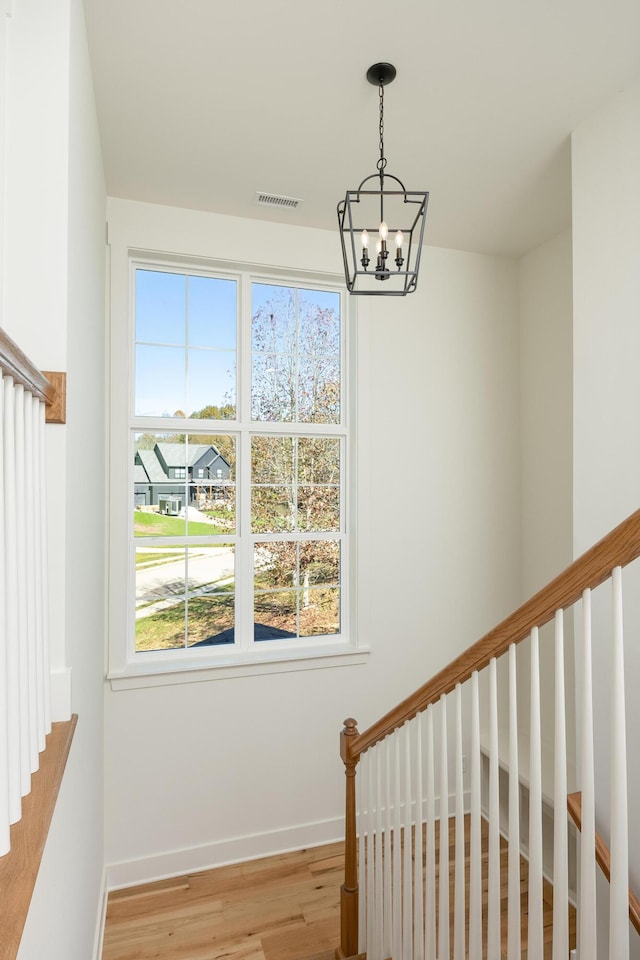 stairs featuring hardwood / wood-style floors and an inviting chandelier