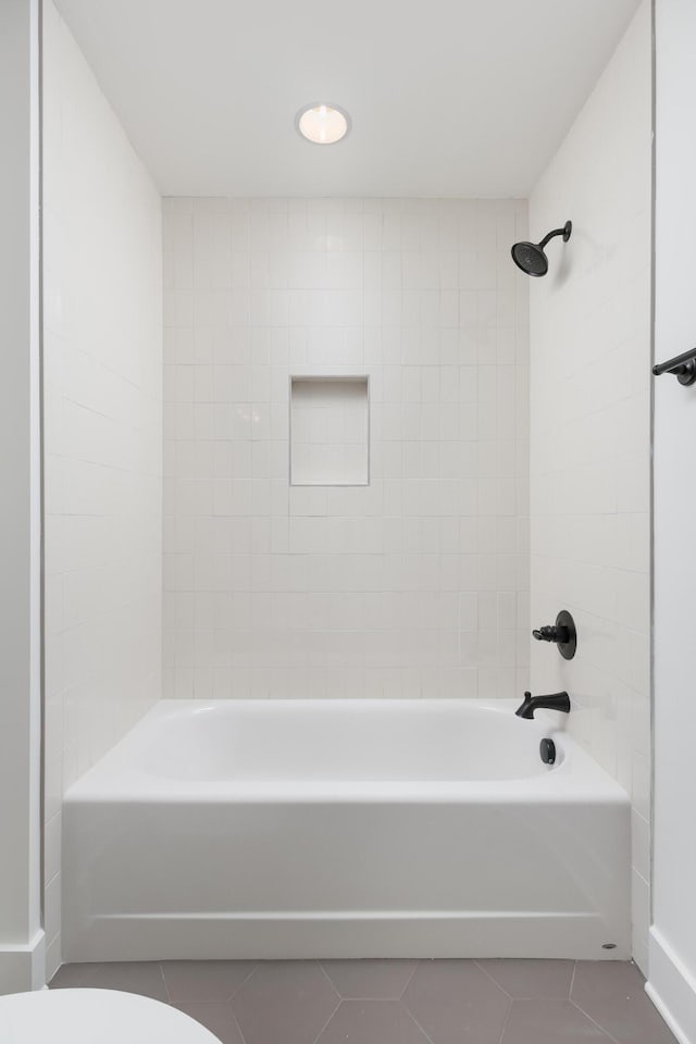 bathroom with tile patterned floors, toilet, and tiled shower / bath