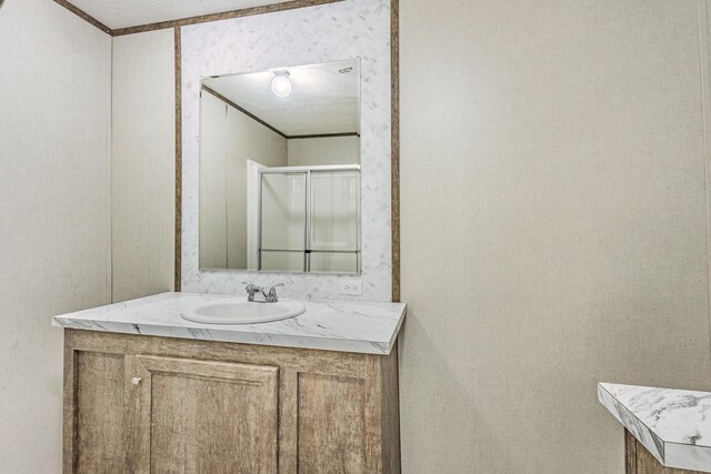 bathroom with vanity, crown molding, and an enclosed shower