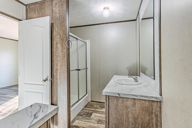 full bath featuring vanity, wood finished floors, a shower stall, and a textured ceiling