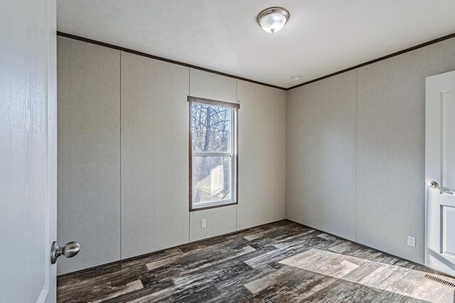 unfurnished room featuring visible vents, ornamental molding, and wood finished floors