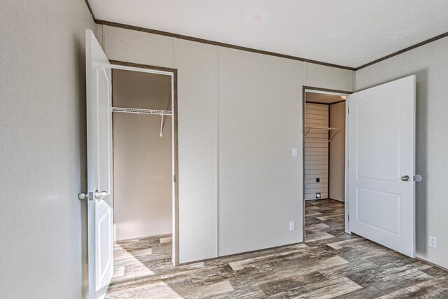 unfurnished bedroom featuring crown molding, wood finished floors, and a closet