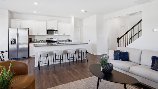 kitchen with white cabinetry, dark hardwood / wood-style flooring, an island with sink, and stainless steel appliances