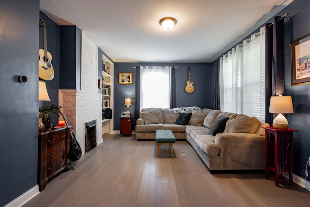 living room with hardwood / wood-style floors, built in features, and a brick fireplace