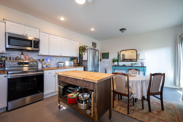 kitchen featuring white cabinetry, tasteful backsplash, dark hardwood / wood-style floors, butcher block countertops, and appliances with stainless steel finishes