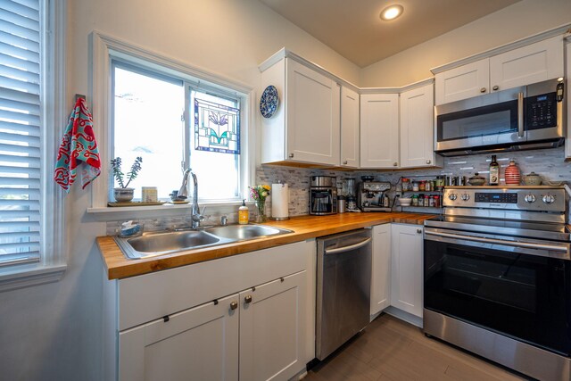 kitchen featuring butcher block countertops, white cabinets, sink, and stainless steel appliances