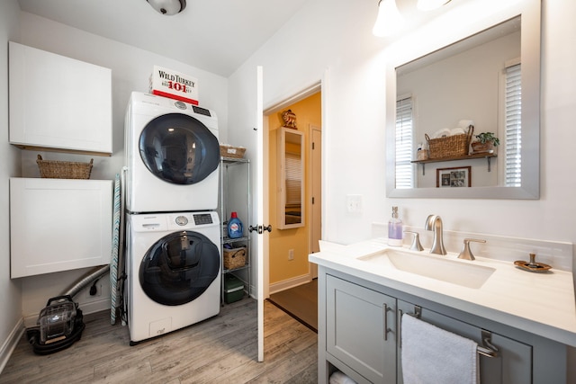 washroom featuring stacked washer and dryer, light hardwood / wood-style flooring, and sink